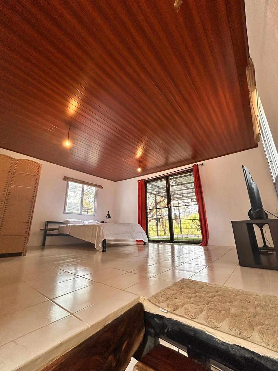 Bedroom with king bed and balcony opening to the jungle