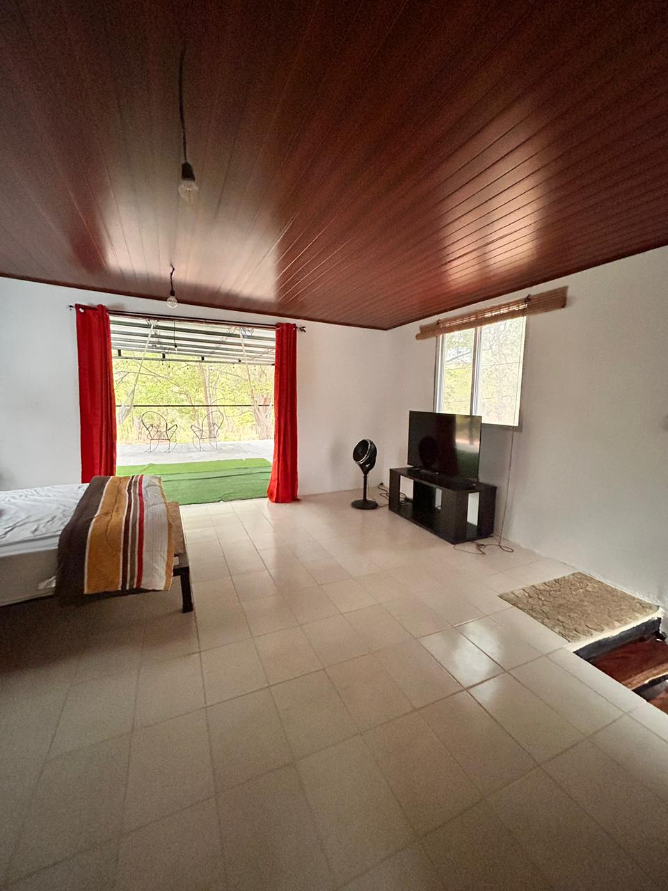 Bedroom with TV area and red curtains opening to the terrace