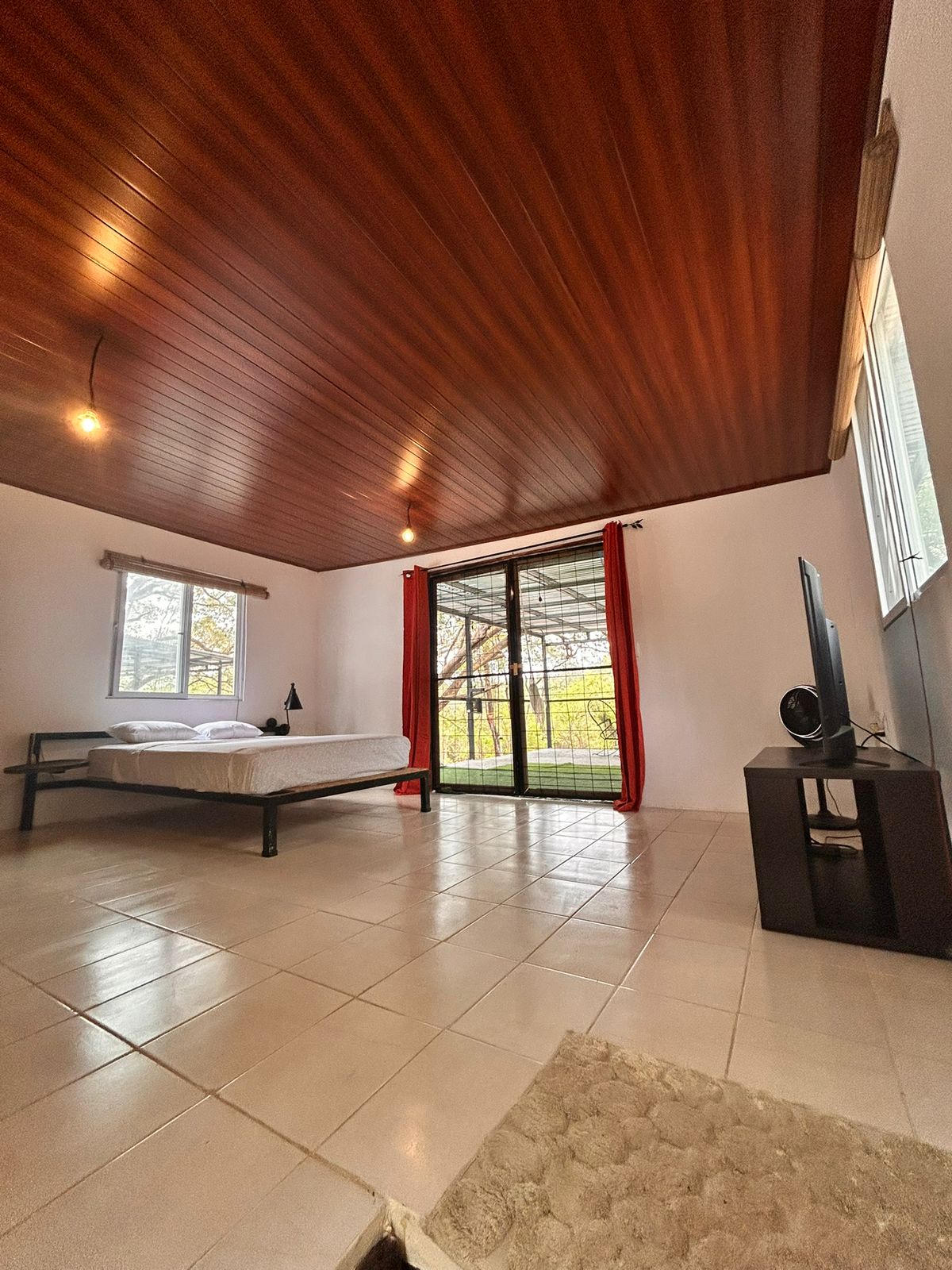 Spacious bedroom with wooden ceiling and jungle-view balcony